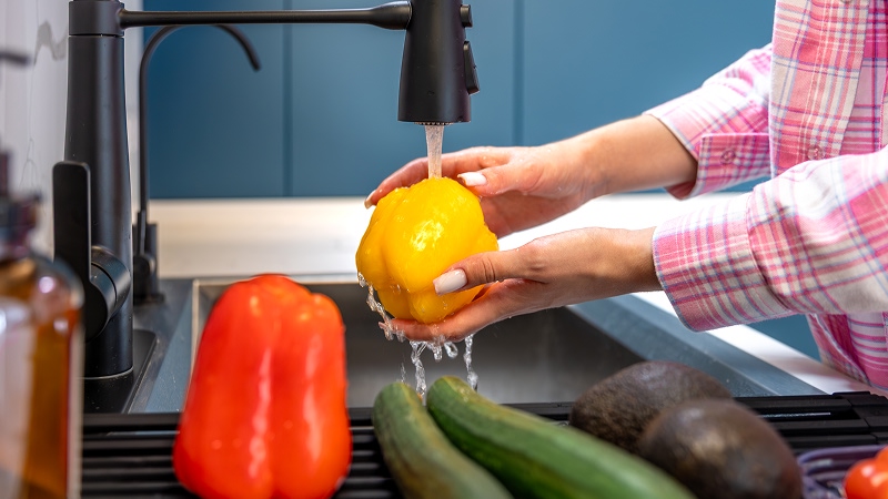 женщина моет овощи под краном